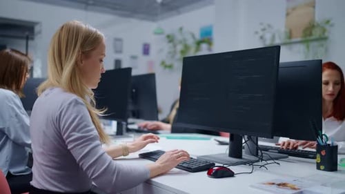 Young Adult Women In Modern Office IT Professionals Sitting At Tables And Working With Computers