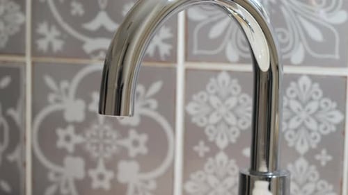 Water is dripping from a chrome bathroom tap