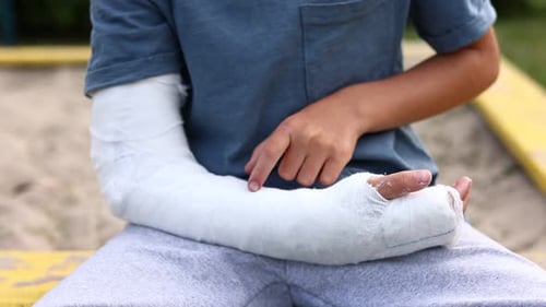 kleiner Junge mit gebrochenem Glied im Freien. Der Arm eines Kindes ist gebrochen. Bruchverletzung im Sommer