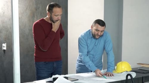 Architects Discussing Blueprints Indoors at Table