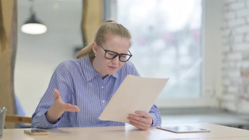 Blonde Woman Frustrated with Paperwork in Office