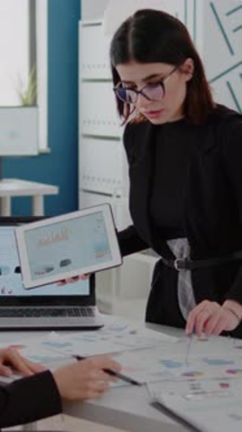 Vertical Video Office Workers Using Laptop and Tablet with Data Charts