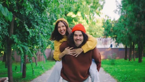 A Joyful Man and Woman are Seen Enjoying a Playful Moment in a Vibrant Green Park Man Gives a Girl a