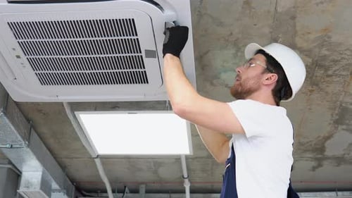 Professional Technician Maintaining Modern Air Conditioner in Office