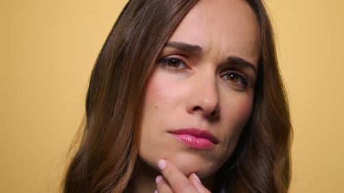 Pensive Woman Deep in Thought on Beige Background