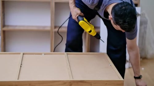 Man Assembling Furniture with Power Drill Indoors