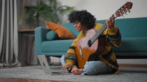 Woman Playing Guitar at Home with Laptop