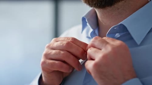 Man Buttons Blue Shirt in the Office
