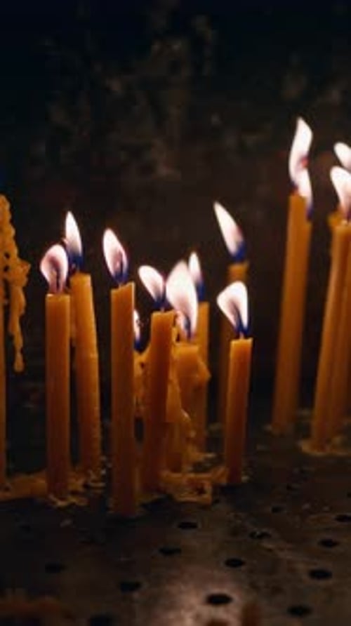 Close up of multiple stick candles burning in a church. Vertical