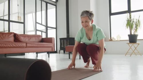 Woman Unrolls Yoga Mat and Stretches Indoors