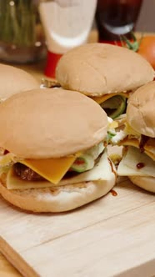Vertical video. Homemade Burgers on a Wooden Table, with ingredients placed nearby along with sauce