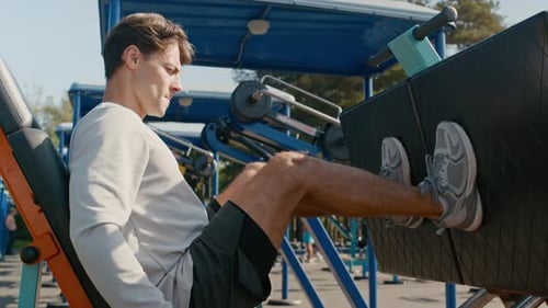 Man Exercising on Leg Press Machine Outdoors Daytime