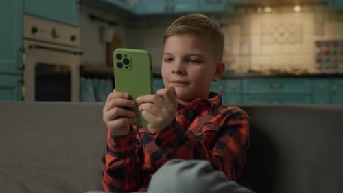 Boy Using Smartphone on Sofa at Home