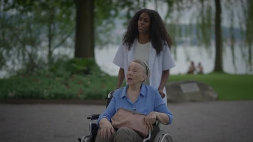 A Compassionate Caregiver is Assisting an Elderly Woman in a Beautiful Serene Park Setting