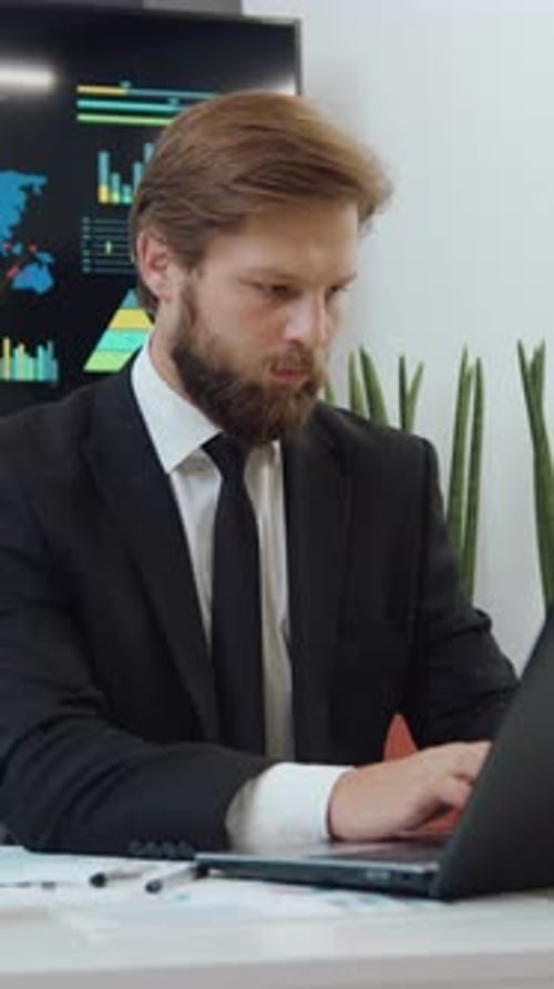 Focused Businessman Working on Laptop in Modern Office