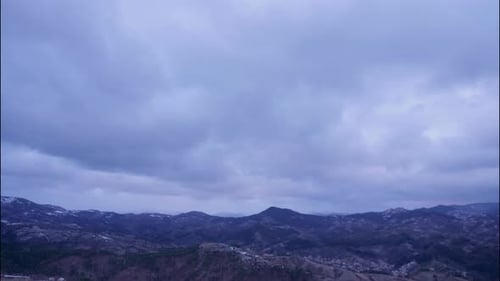 Sunrise in the mountain above city in windy winter, time lapse