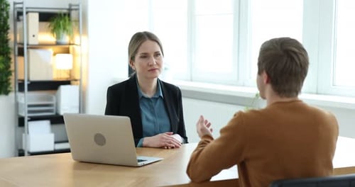 Recruiter with laptop and candidate having job interview at table in office