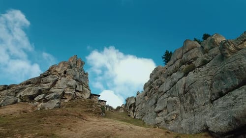 Static Wide Shot of Dramatic Rock Formations and a Mountain Hut Against a Blue Sky