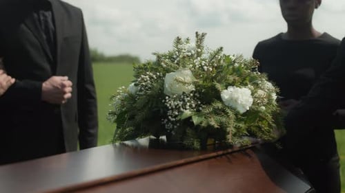 Mourners Gather at Coffin in Bright Green Field