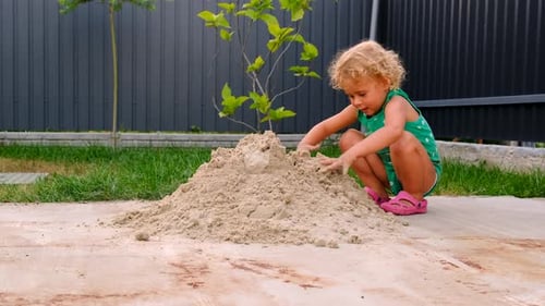 Adorable Child Playing with Sand in Backyard