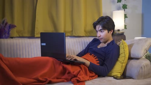 Homme heureux utilisant un ordinateur portable couché.
