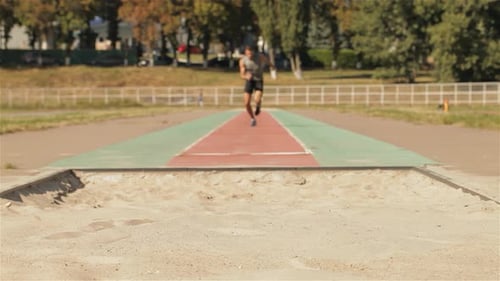 Caucasian Male Athlete Suffers a Painful Landing After Long Jump