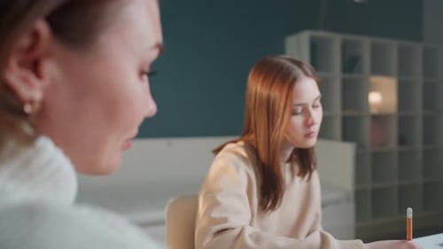 Étudiante immergée dans ses devoirs avec un tuteur de soutien à proximité Une étudiante disciplinée