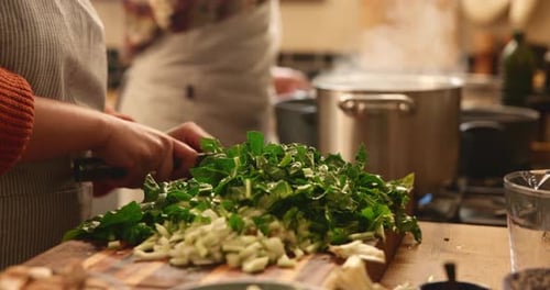 Chopping Green Vegetables on Cutting Board in Kitchen