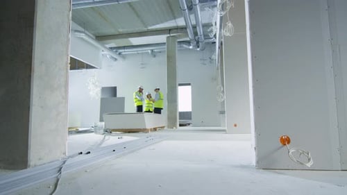 Team of Engineers in Hard Hats Having Conversation, Looking at Blueprint, inside Building Under Con