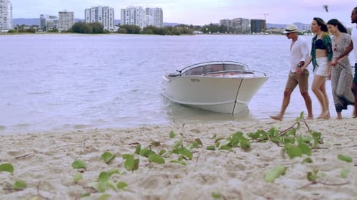 Friends enjoying a sunset beach walk past a boat in coastal Australia