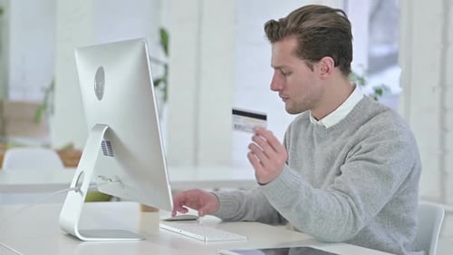 Konzentrierter junger Mann, der Online-Zahlungen auf dem Desktop tätigt