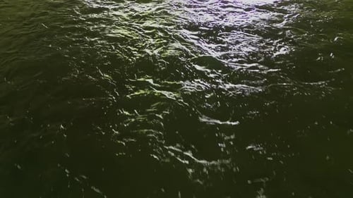 drone shot top down angle rippling deep dark water highway underpass in America