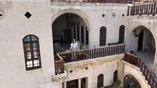 Woman on Ornate Balcony of Historical Building