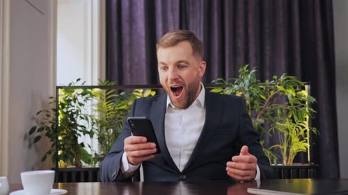 Man Receives Good News on Phone at Desk