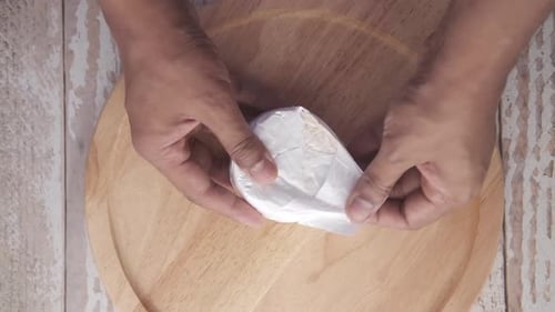 Hands Unwrap Fresh Cheese on Cutting Board