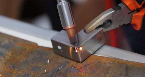 Laser welding machine with hand hold gun. Laser welding is shown in close-up.