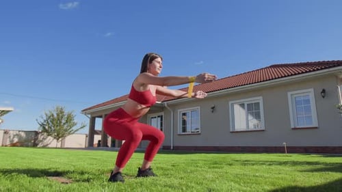 Athletic Woman Exercising with Resistance Band Outdoors