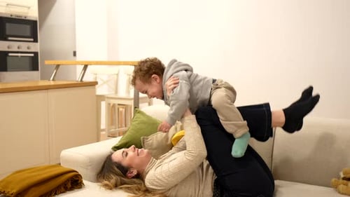 Woman Lying on Couch Playing with a Child