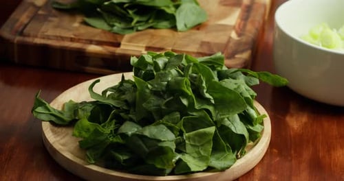 Closeup A Chef Arranges Fresh Spinach on a Wooden Cutting Board on a Wooden Table Fresh Greens are