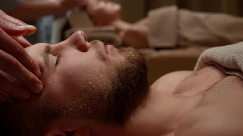 Peaceful Bearded Man Receiving Professional Head Couples Massage Therapy in Calming Spa Setting