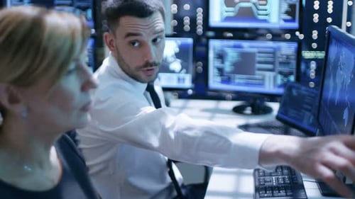 Foto de
Dolly de ingenieros trabajando en sus computadoras en la sala de monitoreo. Muchas pantallas con varios días