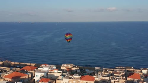 Hot air balloon passing over Acre old city port houses and Mosque at sunrise, Aerial view
