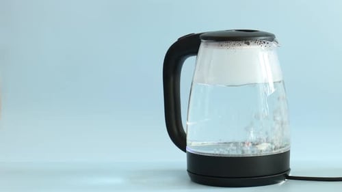 Woman turning on electric kettle against light blue background, closeup