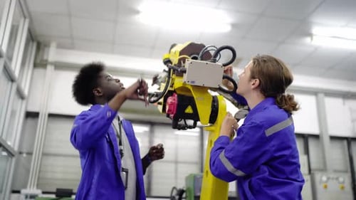 Engenheiros inspecionando e verificando a máquina automatizada de robôs de soldagem de máquinas de armas na fábrica.