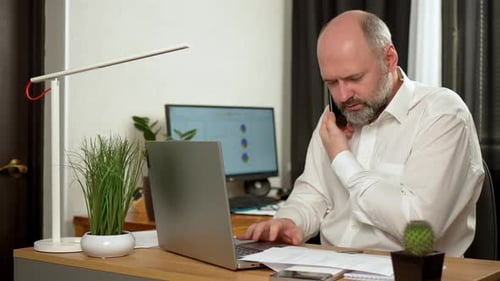 Man Working at Desk Talking on Phone