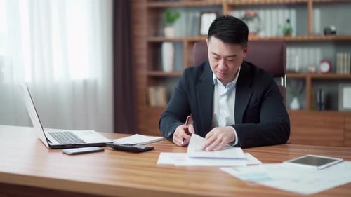 Man Works at Desk Reviewing Documents