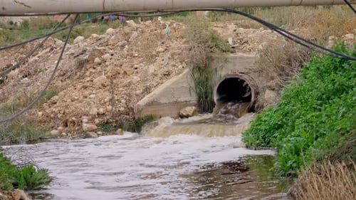sewage flowing from a pipe into a stream