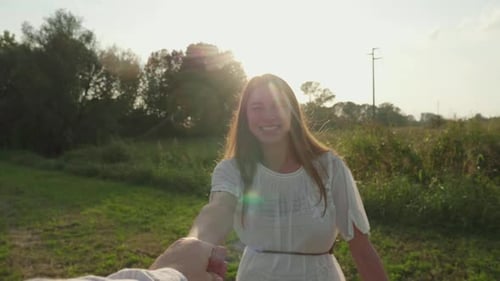 Authentic shot of carefree young woman is keeping a hand of beloved man and enjoying a nature with
