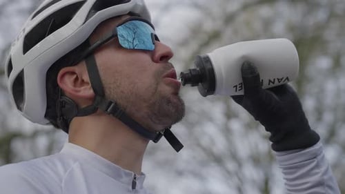 Cyclist drinking water from bottle during outdoor road ride