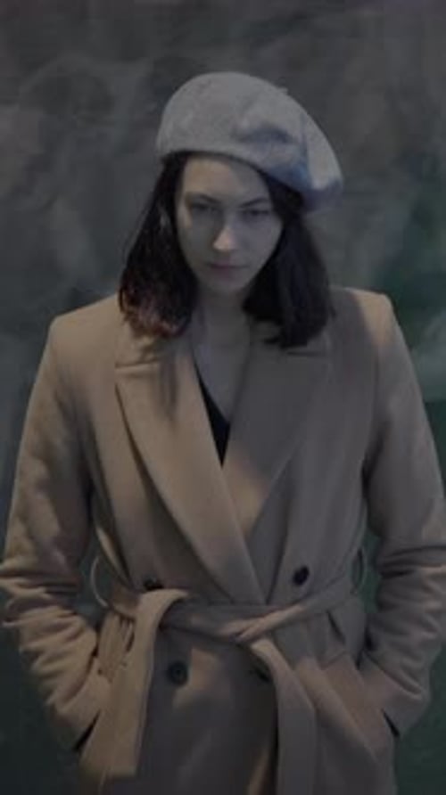 Una mujer elegante con una boina y un abrigo posó con gracia en un entorno urbano de la ciudad